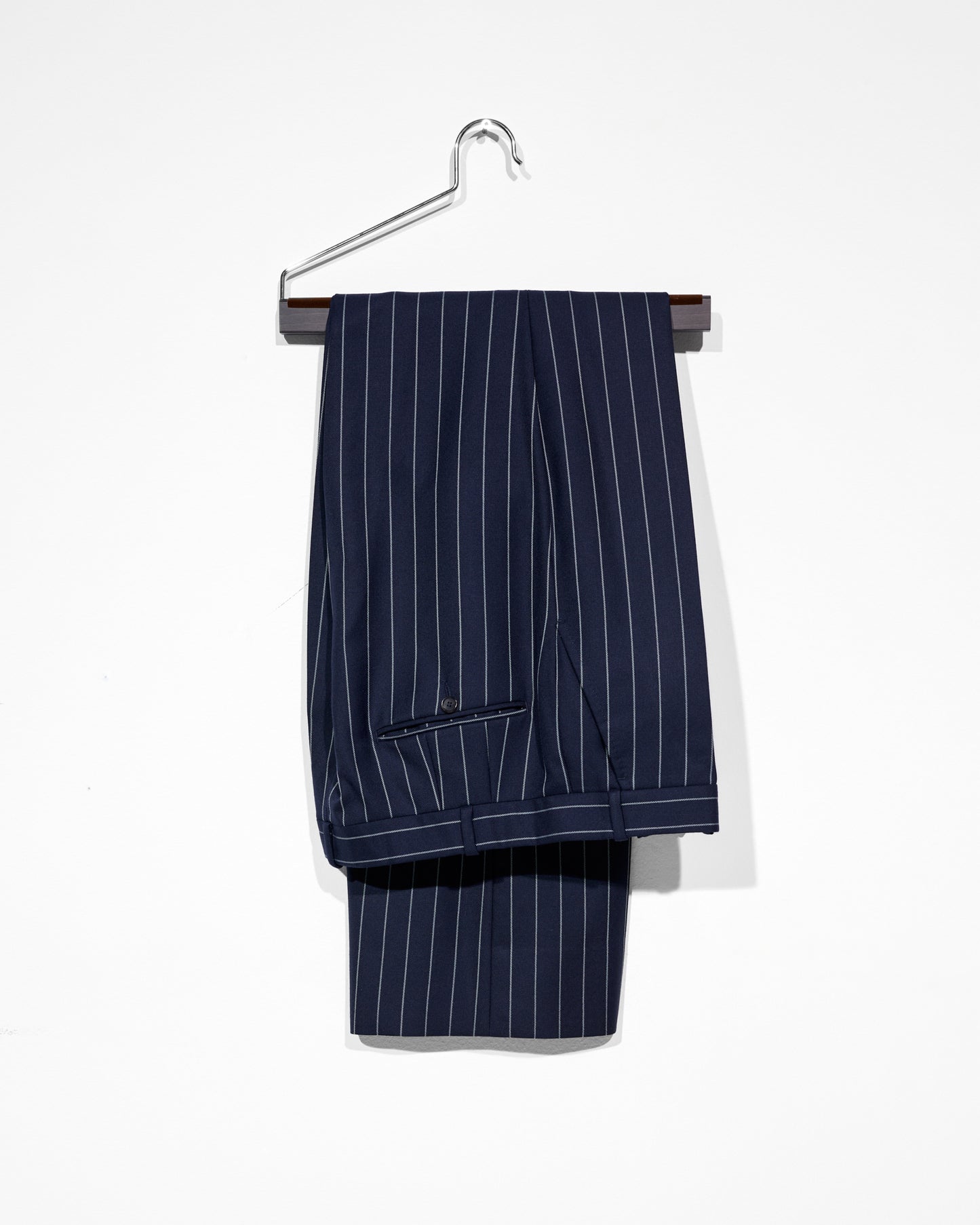 Navy pinstripe suit pants on a hanger against a white background