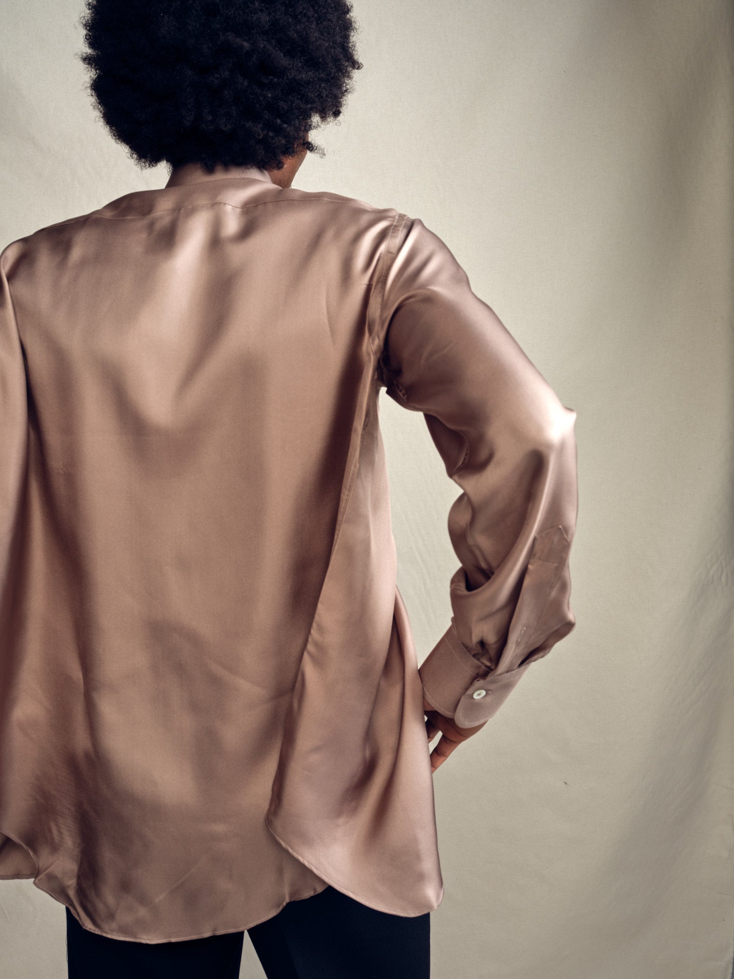 Model wearing Biboja champagne beige silk shirt, single cuff detail.