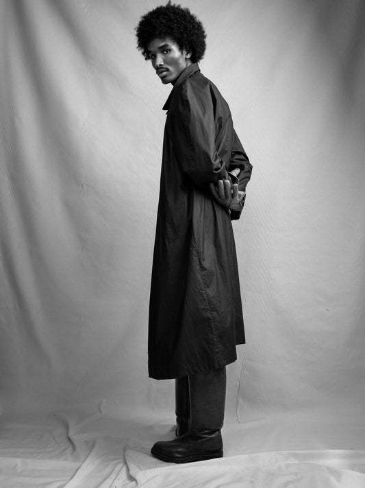 Person wearing a long navy Turnbull & Asser car coat in cotton against a plain background